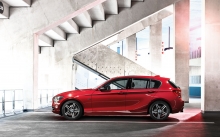 Взгляд в профиль на блестящий красный BMW 1 series в стенах городской парковки